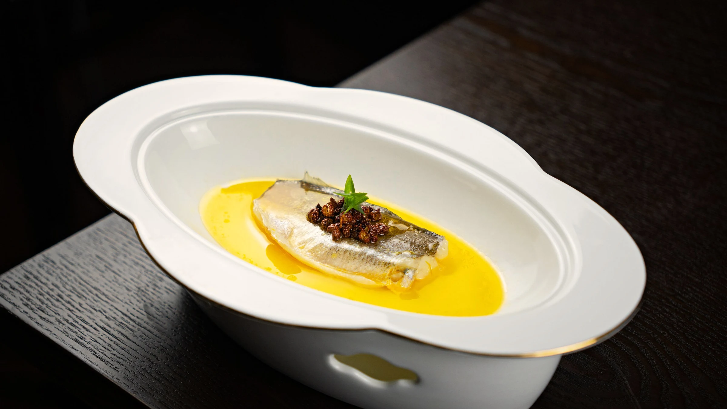 Fotografía de referencia: filete de pescado en salsa amarilla, servido en un plato blanco de borde dorado.