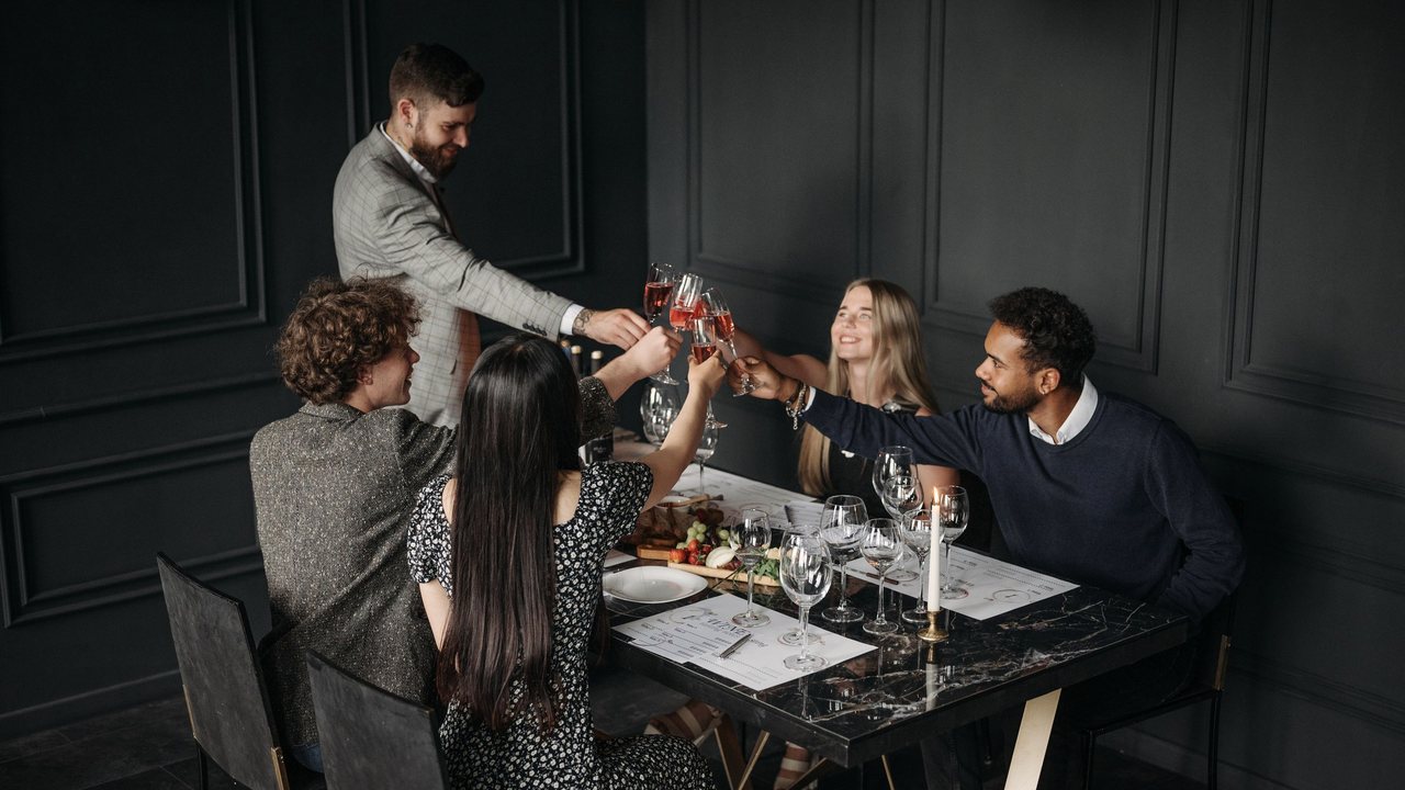 Fotografía de referencia: un grupo de amigos brinda durante una cena elegante.