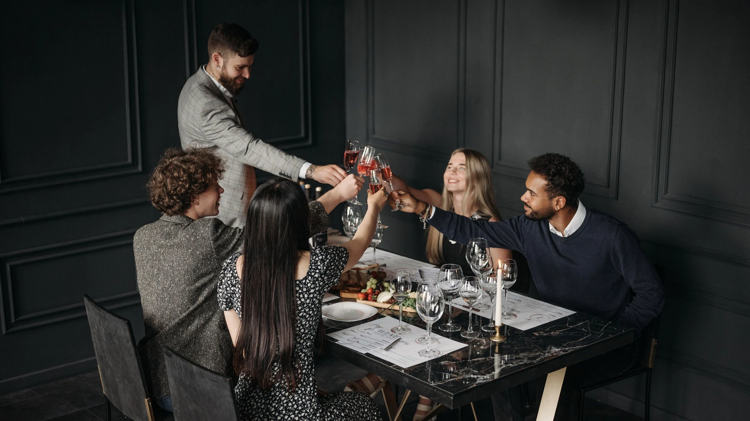 Fotografía de referencia: un grupo de amigos brinda durante una cena elegante.